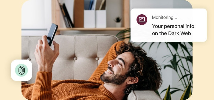 Man smiling while lying on a couch and looking at a mobile phone