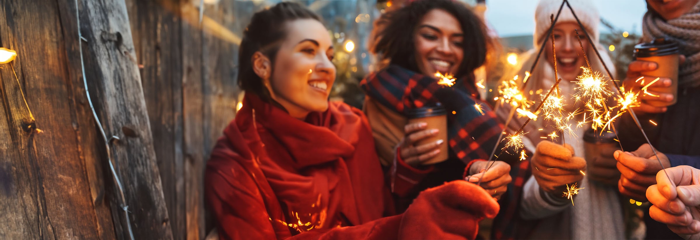 A young couple staring in the window of a store surrounded by Christmas lights and décor.