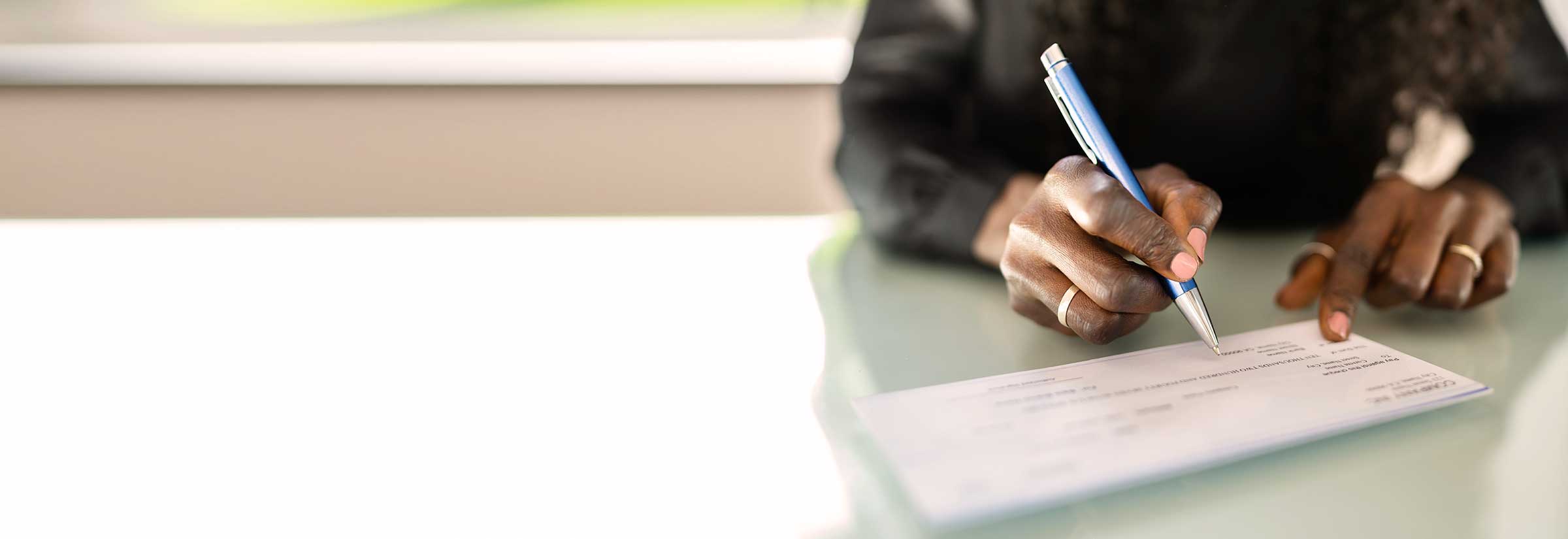 Someone writing a new check to be sent in the mail, hoping they don’t become a victim of check washing.