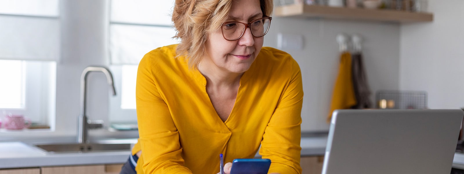 Photo of a woman considering a credit lock vs. freeze as she looks at her phone and computer.