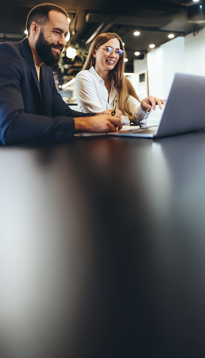 A man with a woman look at a laptop screen and take notes  about LifeLock Editorial Policies.