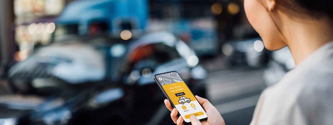 Image of a woman holding on a phone and standing on a street.