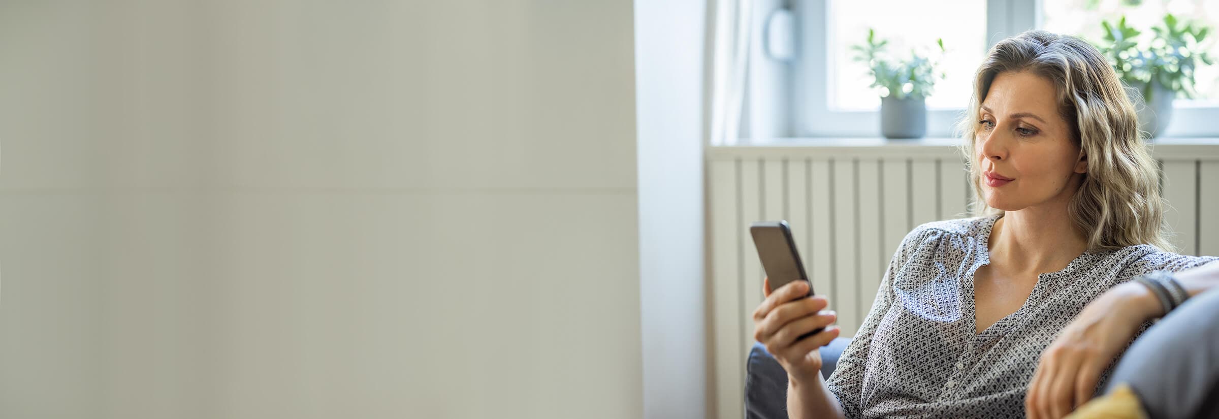 An image of a woman lounging and researching how to identify a fake text message.