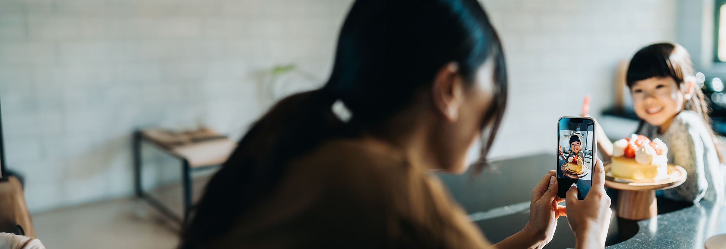 A woman taking a picture of her young child on her mobile phone.