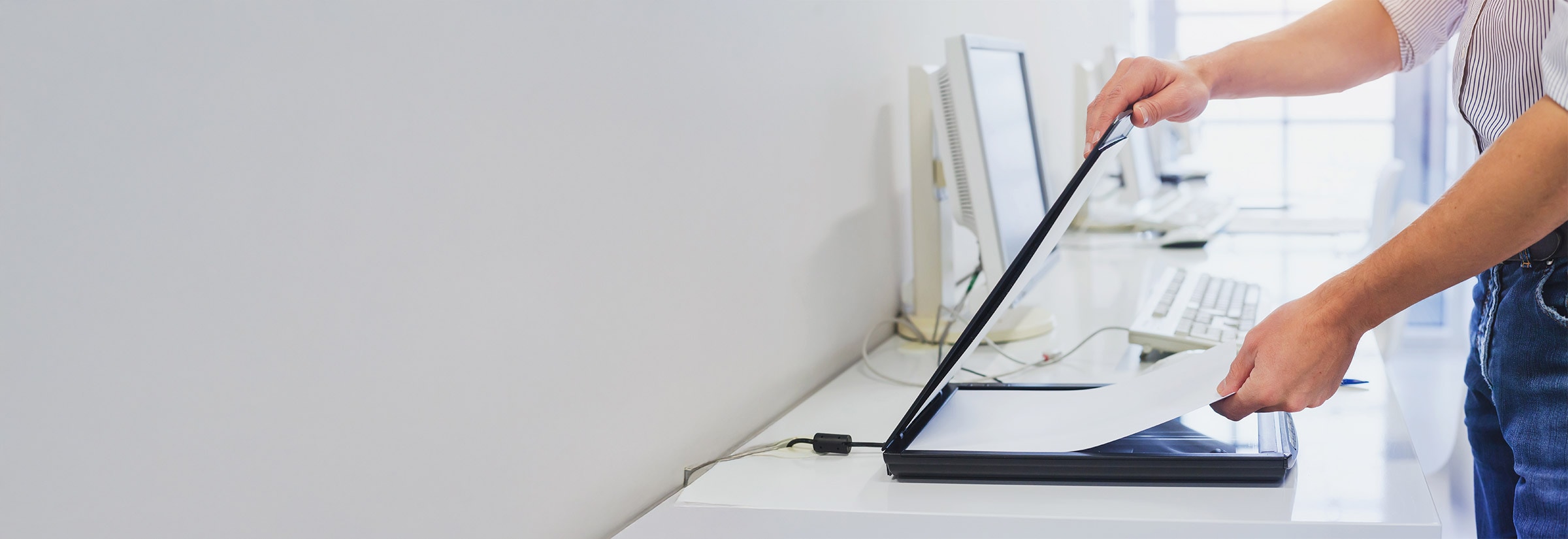 Person operating a scanner on an office desk, scanning sensitive documents safely.