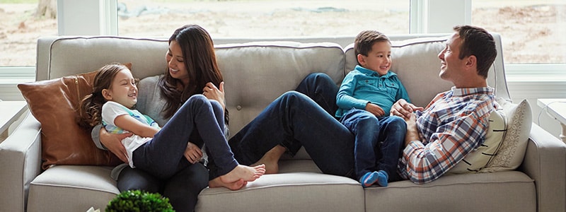 A family of four sits happily on a couch after learning about how to help protect against identity theft.