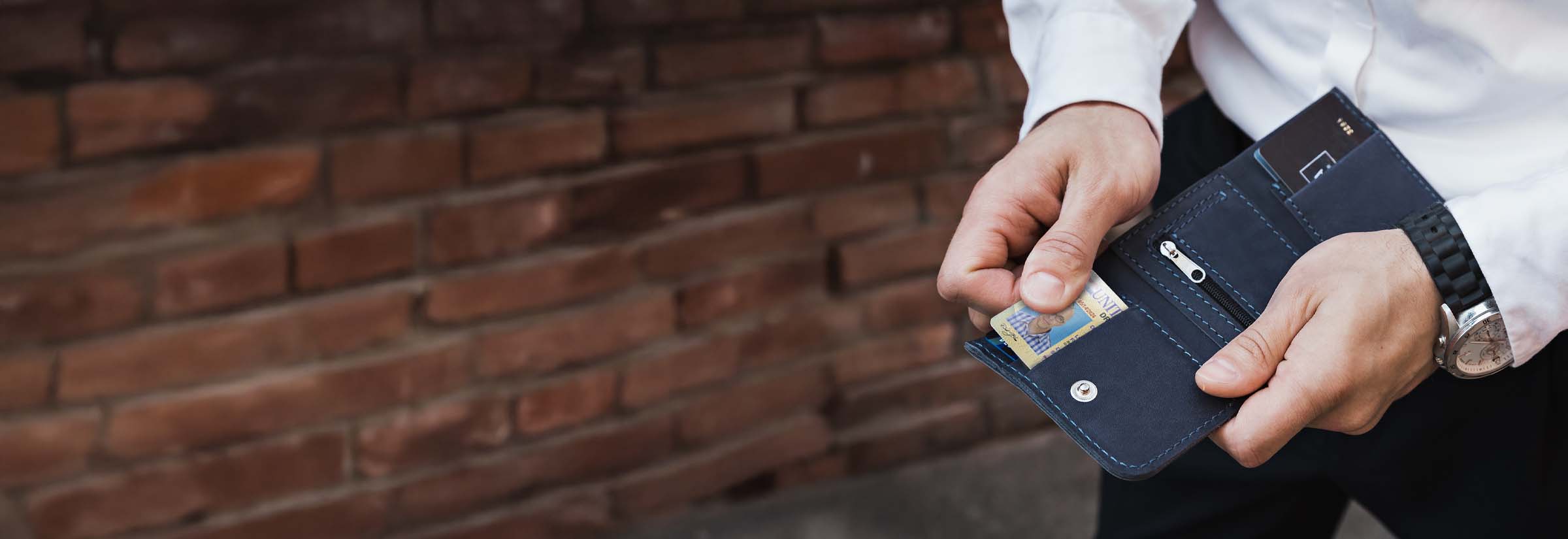A person pulling a driver’s license out of a wallet.