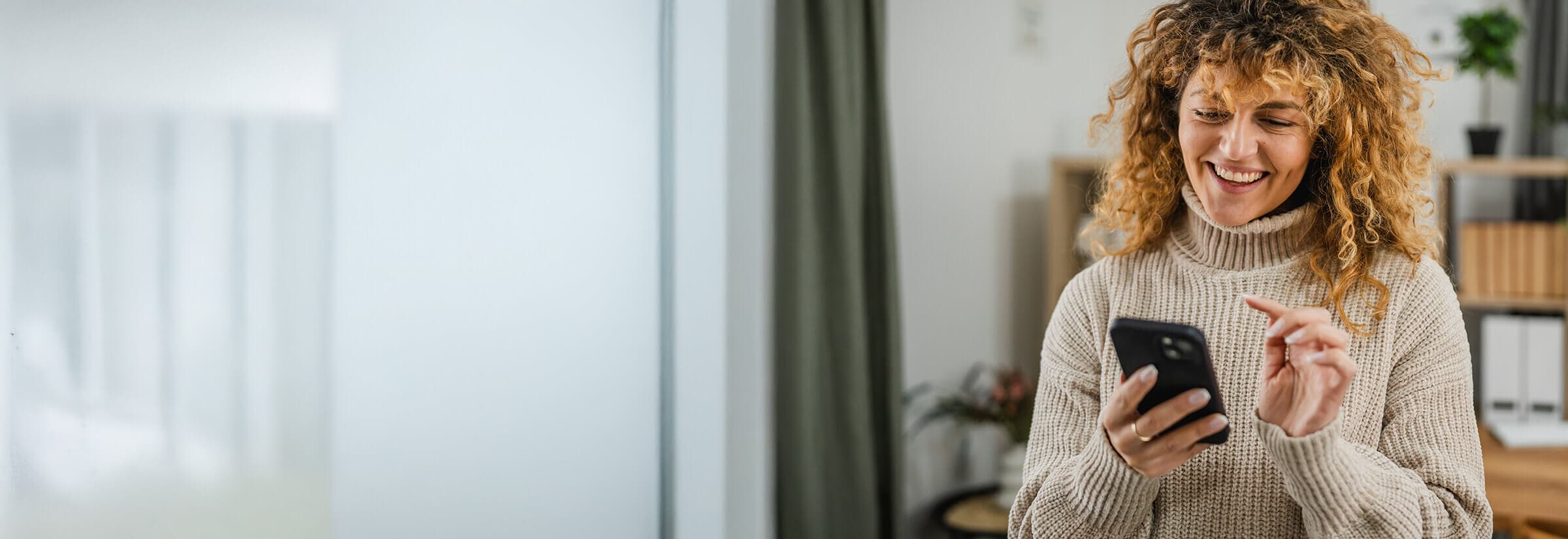 A smiling person interacts with their phone safely, avoiding WhatsApp scams.