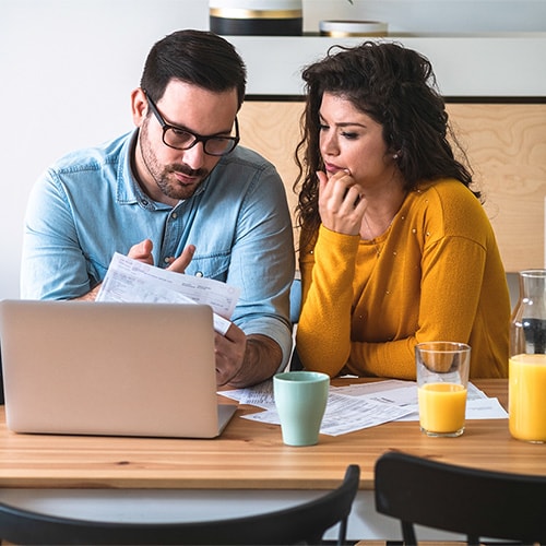 A couple reviews their statements to assess the damages of a recent bank scam.