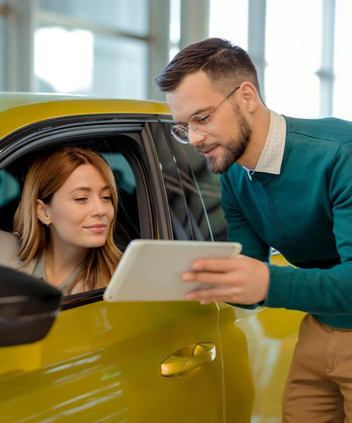 A car salesman helps a woman buy a car.