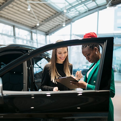 A car salesman shows a woman that she has a good credit score to buy a car. 