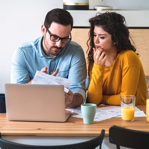 A couple reviews their statements to assess the damages of a recent bank scam.