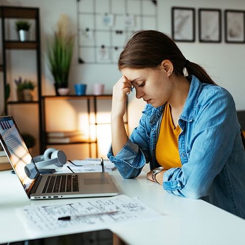 Woman sitting at a desk with a laptop researching the National Public Data breach.