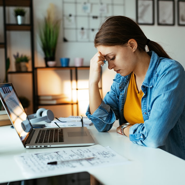 Woman sitting at a desk with a laptop researching the National Public Data breach.