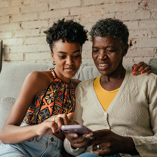 Two women analyze a text message that appears to be from Publishers Clearing House.