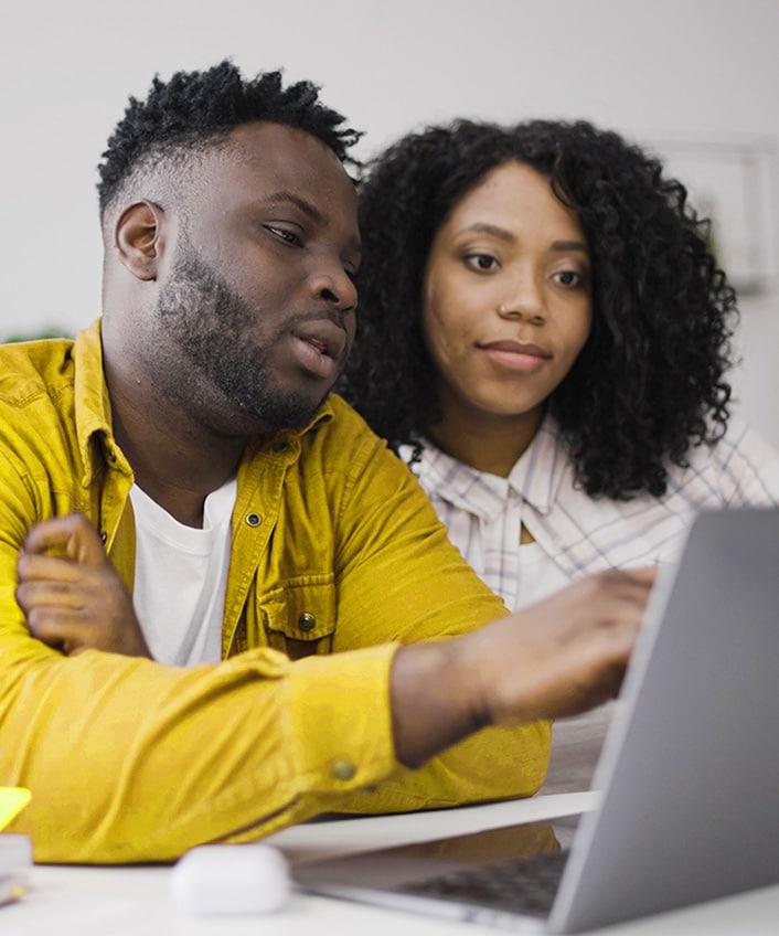 A couple looking at their computer learning about how to avoid real estate scams.