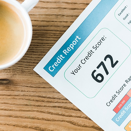 Woman with a coffee mug looking at her phone to look up what a good credit score is.